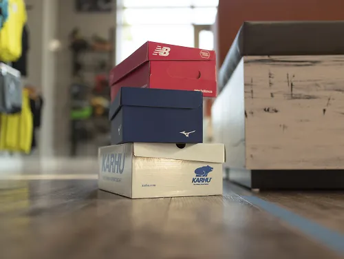 Different brands running shoes on the floor of a Fleet Feet ready to be tried on