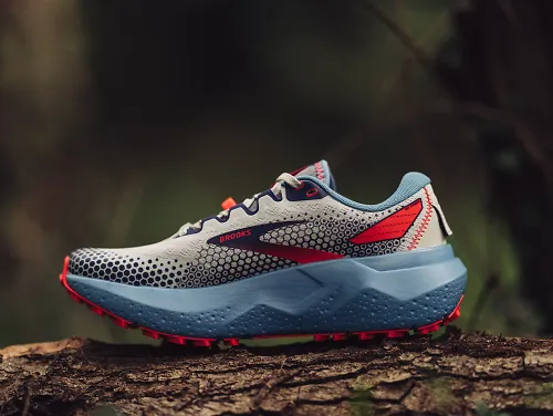 The women's Brooks Caldera 6, a trail running shoe, sits on a tree.
