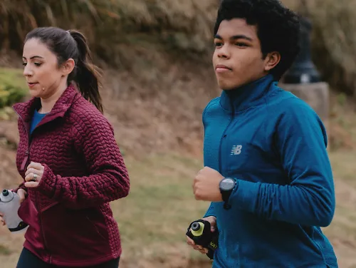 A woman and man run together in the winter