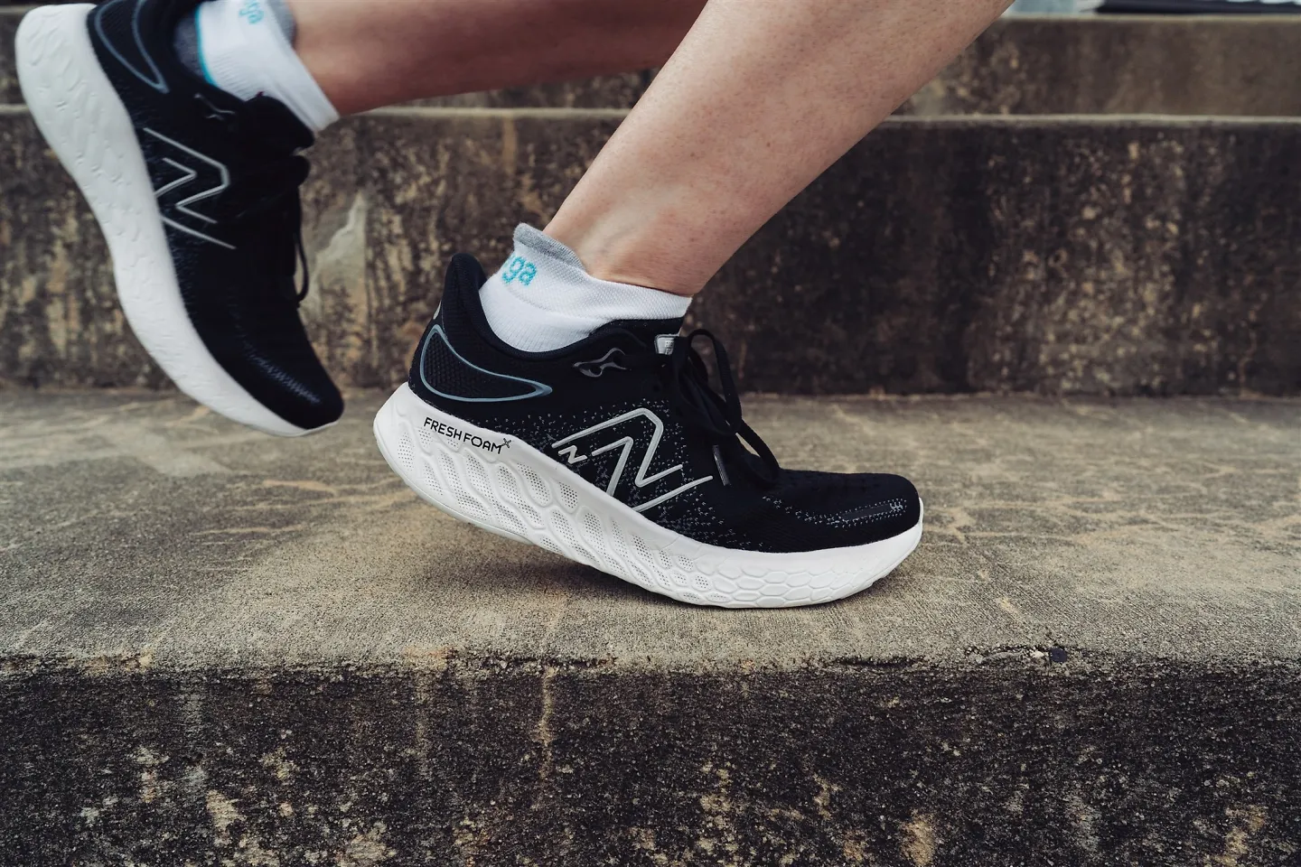 A woman running on stairs in a pair of New Balance Fresh Foam X 1080 v12.