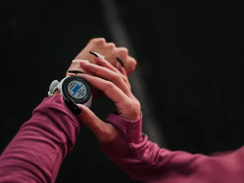 A runner sets her Garmin watch up to record a workout.