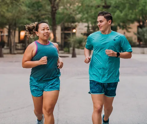 A woman and man run down a sidewalk together wearing rabbit clothes 