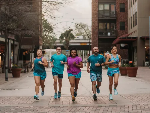 5 runners running down a sidewalk in Fleet Feet Exclusive rabbit Apparel