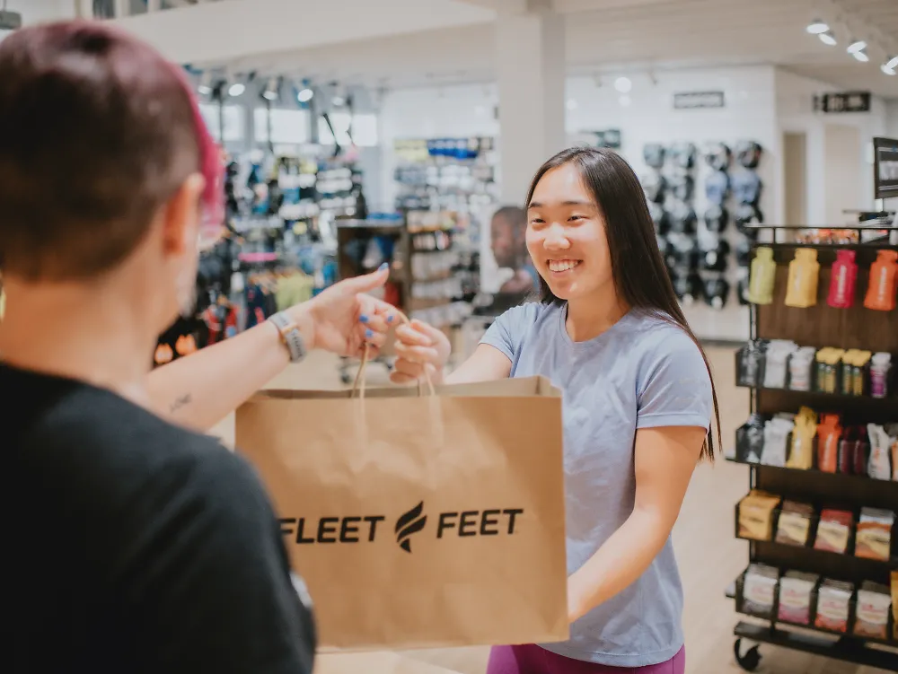 A customer smiles as she receives her Fleet Feet bag. 