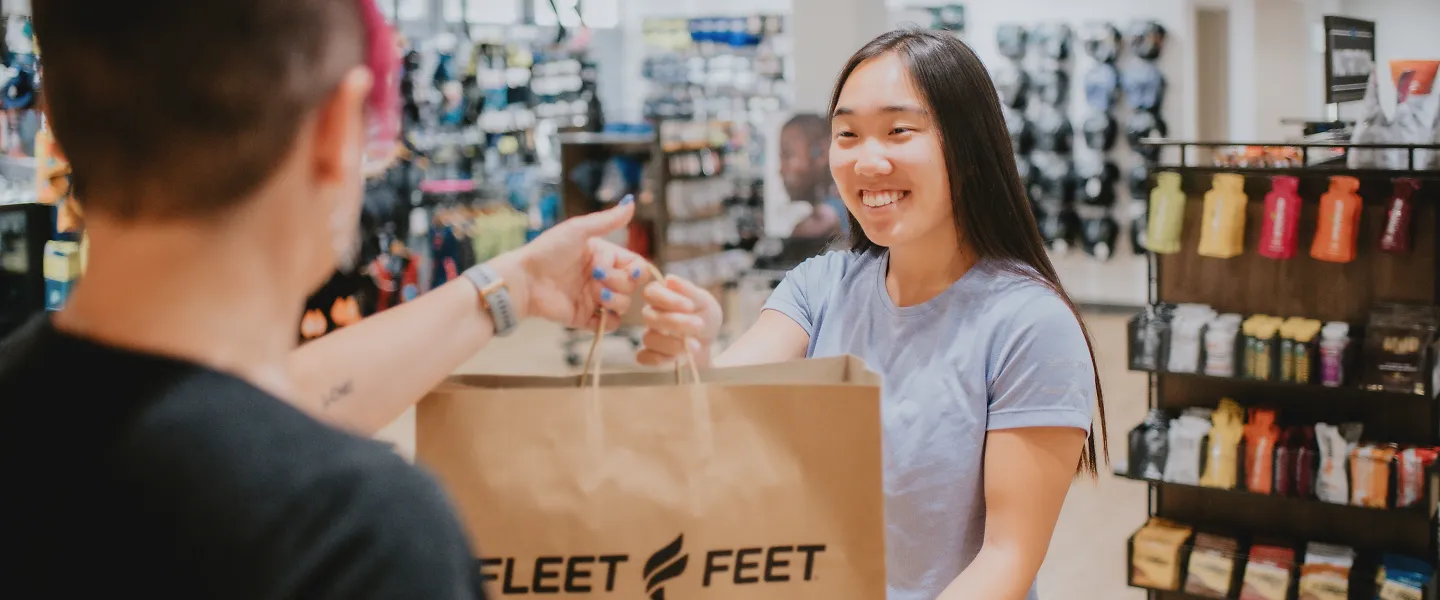 A customer smiles as she receives her Fleet Feet bag. 