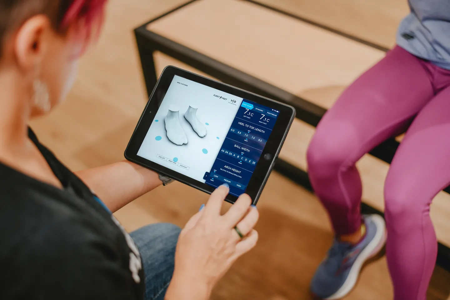 A Fleet Feet outfitter looks at a customer scan and helps her find the perfect shoe