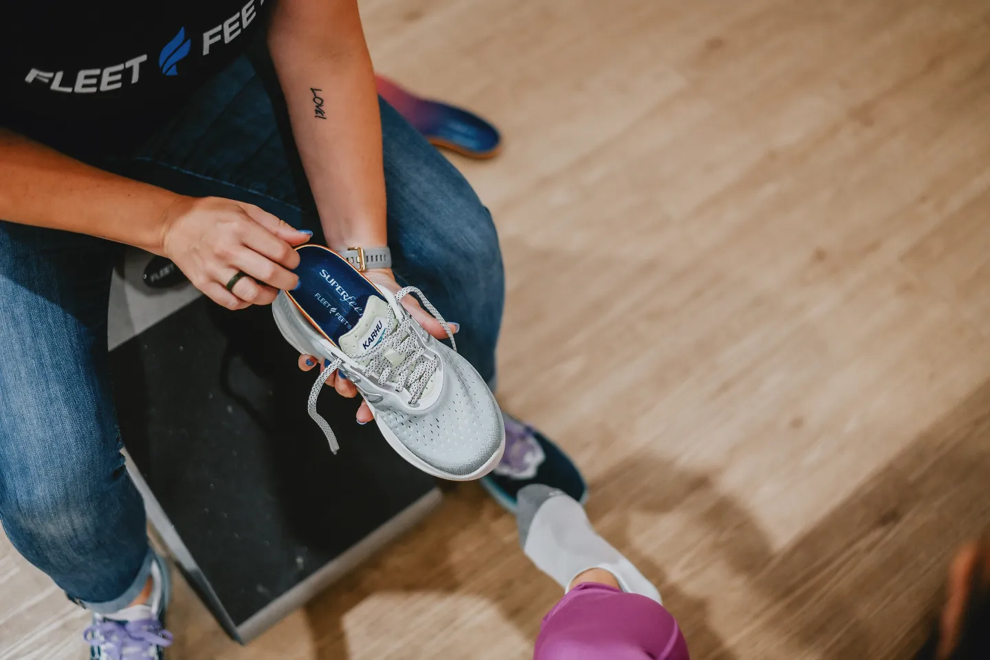 An outfitter puts a pair of insoles into a running shoe.
