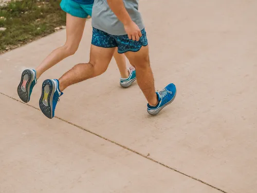 Showing off some of the best Karhu running shoes, a male and female runner are running on a sidewalk in Karhu Synchron