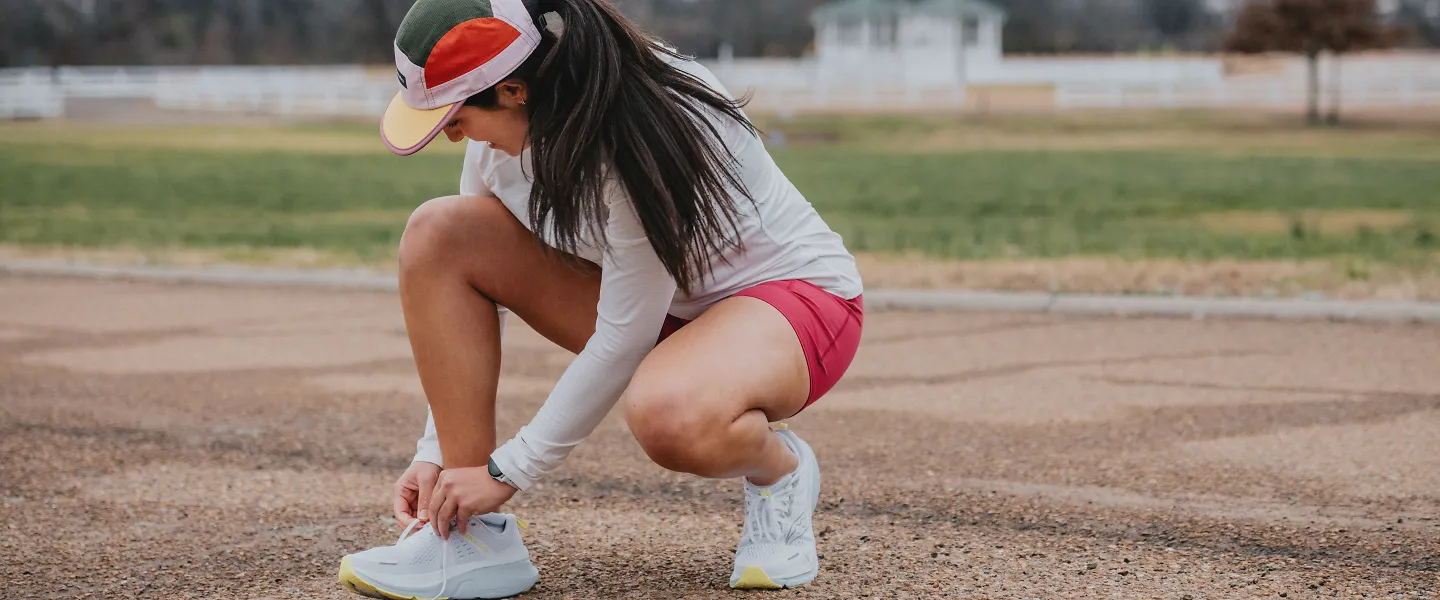 A woman laces up her running shoes. 