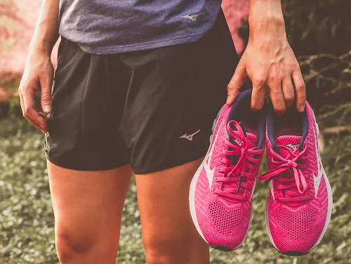 A woman holding a pair of Mizuno running shoes