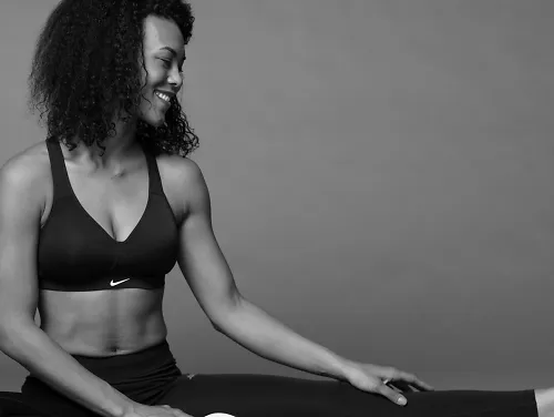 A woman wearing a Nike sports bra stretches her leg