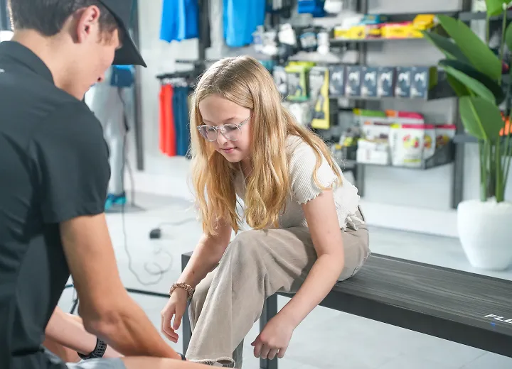 adult male helping female child tie shoe