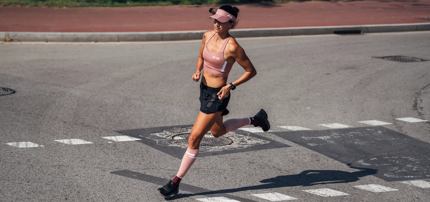 A woman runs in pink CEP 4.0 compression socks