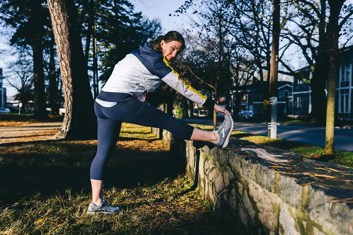 A woman wearing Brooks running apparel stretches her leg before a run