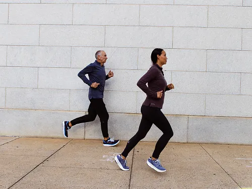 A man and woman run together in cold weather gear from New Balance and Craft. 