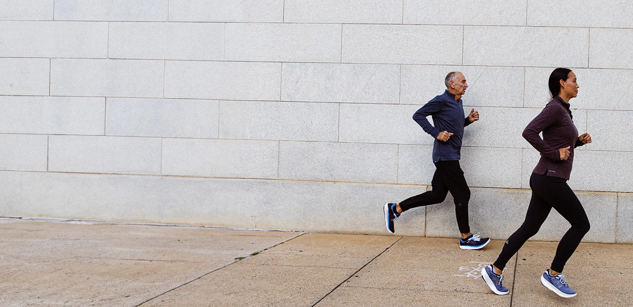 Two runners jogging on sidewalk