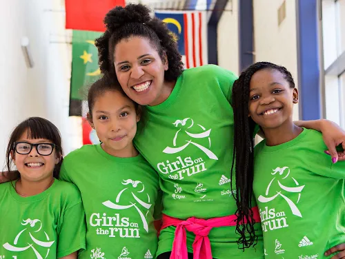 A coach smiles with three girls at Girls On The Run