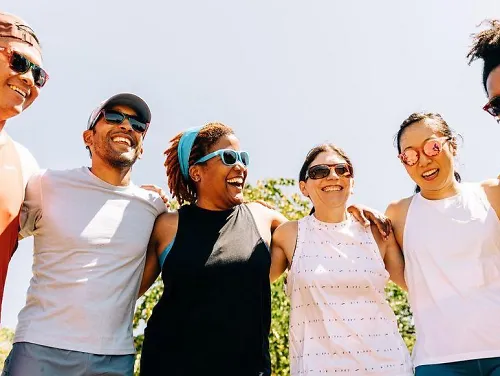 Alison Mariella Desir stands, smiling with a group of friends wearing Brooks running gear