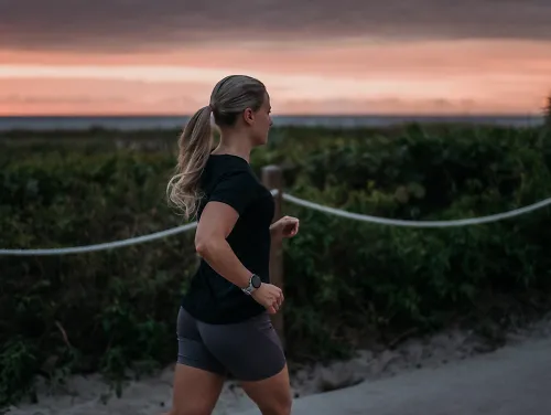 A woman runs alongside a rising sun.