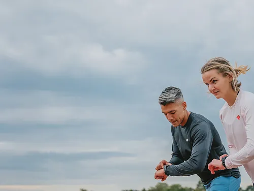 Man and woman setting their gps watches before starting a run