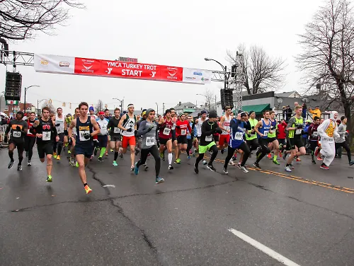 A crowd of runners begins a race at the starting line of the Buffalo YMCA Turkey Trot