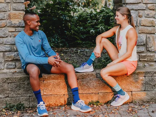 A man and woman sit down in their running clothes to talk about running injuries