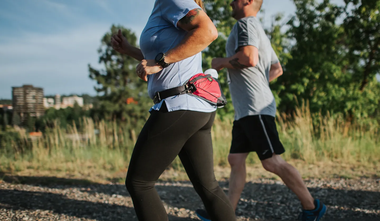 The backs of two runners on a greenway