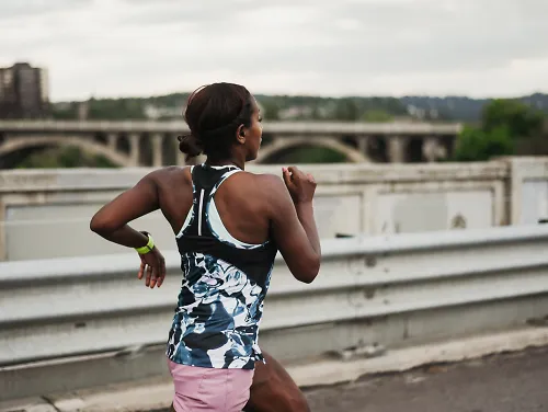 A woman races alone across a bridge
