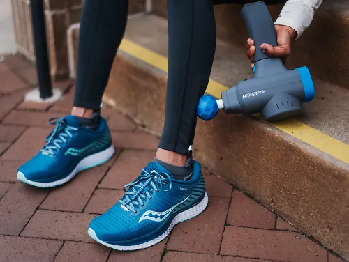 A runner using the addaday BioZoom percussion massager on her leg