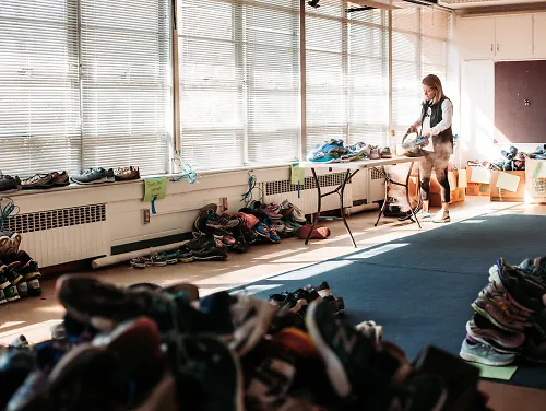Surrounded by shoes, a woman cleans a pair