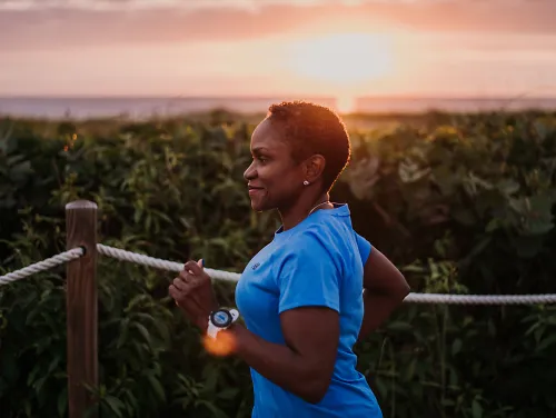 A woman runs as the sun rises.