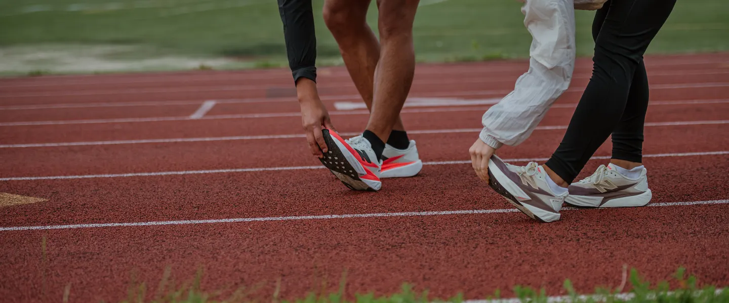 2 people bending over stretching on a track outside