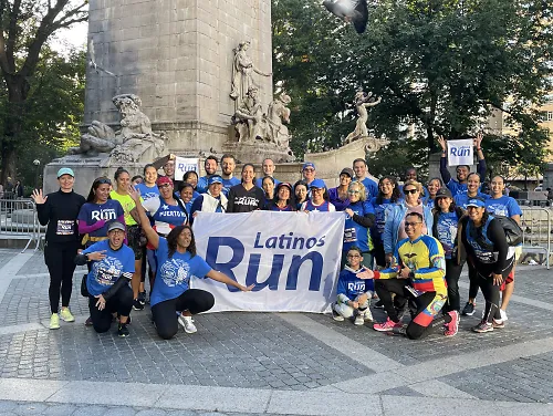 Latinos Run members pose while holding a flag that says Latinos Run.