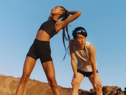 A man and woman stretch after their run wearing new items from the On Spring 2023 Apparel line.