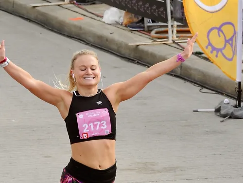 female runner with arms up crossing the finish line of a race