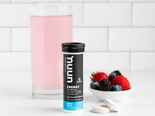 A glass of Nuun energy beside a canister and berries