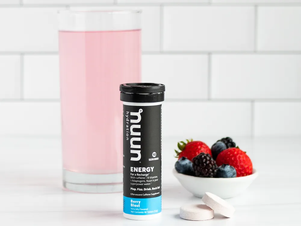 A glass of Nuun energy beside a canister and berries