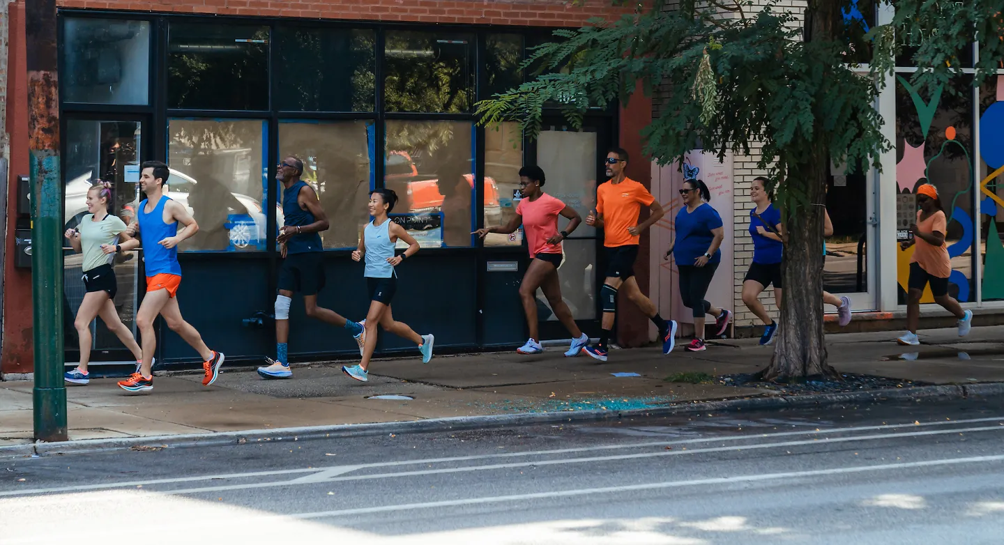 A group of runners runs together along a sidewalk in Chicago