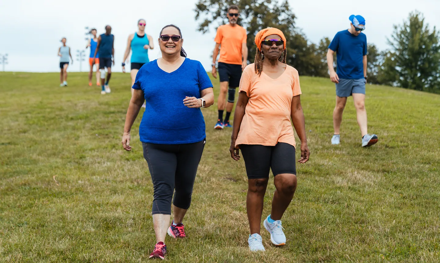 A group of runners walk together down a hill after running a repeat