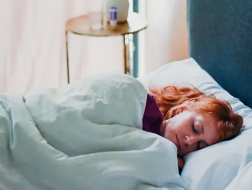 A woman lays in bed sleeping.