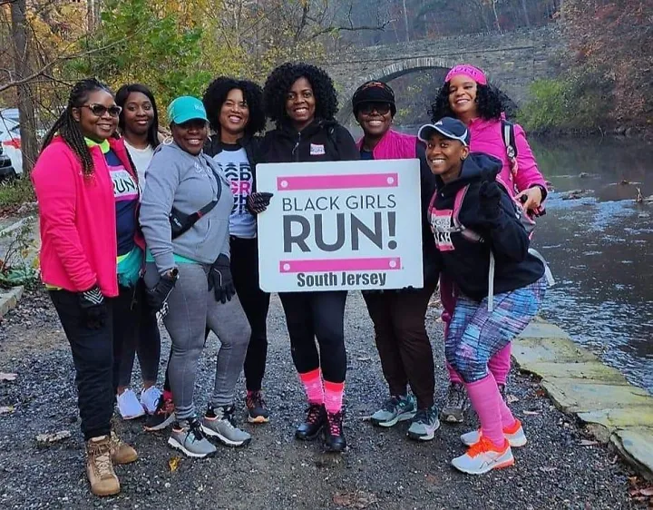 Members of Black Girls Run smile together outside next to a creek