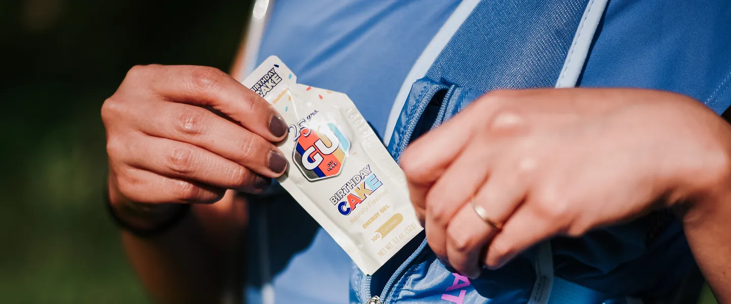 A runner pulls a GU gel from her pack