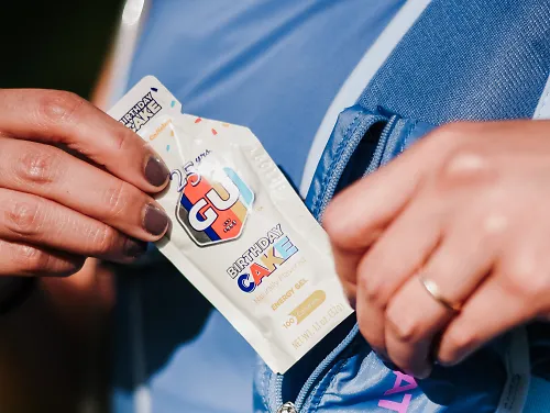 A runner pulls a GU gel from her pack