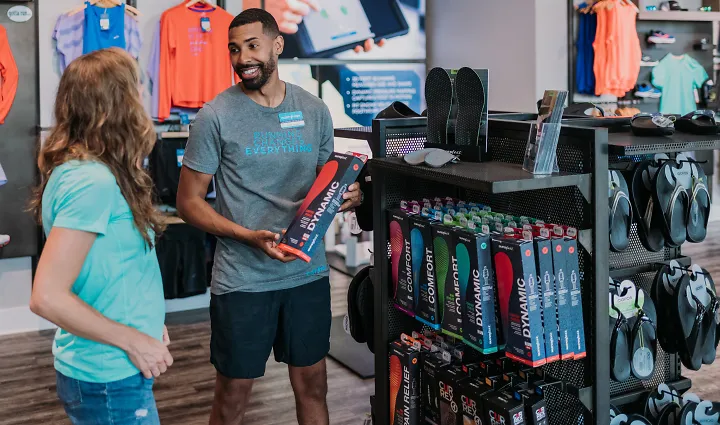 A Fleet Feet outfitter looks at a female customer as he shows her a Superfeet insole  box