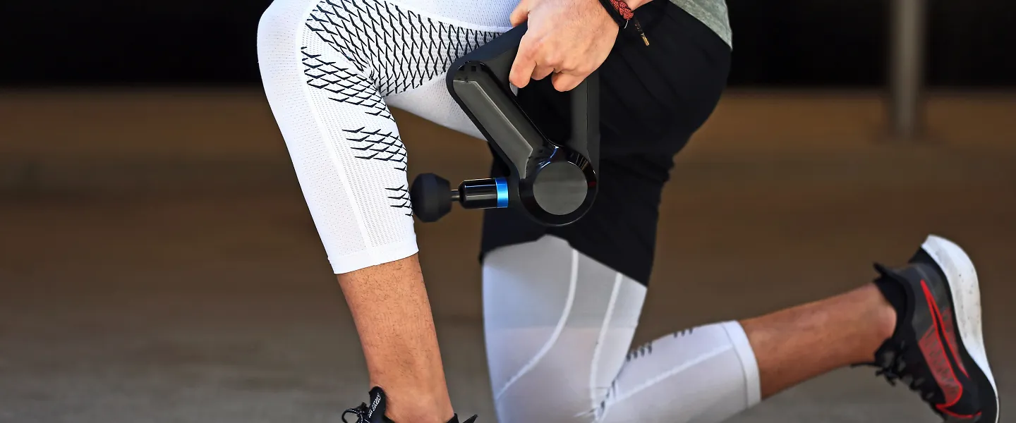 A runner uses the Therabody Theragun Elite massage gun on their calf.