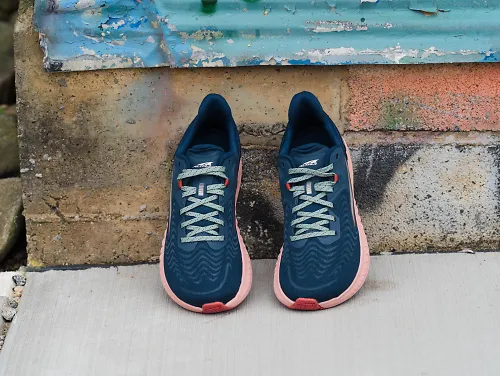 A pair of the women's Altra Torin 7 sits propped up against a wall.