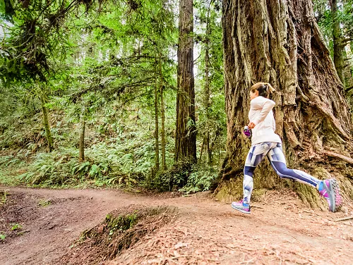 Woman trail running through the woods