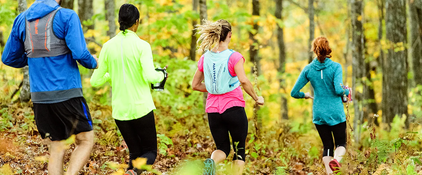 A group of trail runners runs through the woods