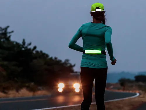 A runner wearing the Amphipod Microstretch-Flash Waistpack while running at night