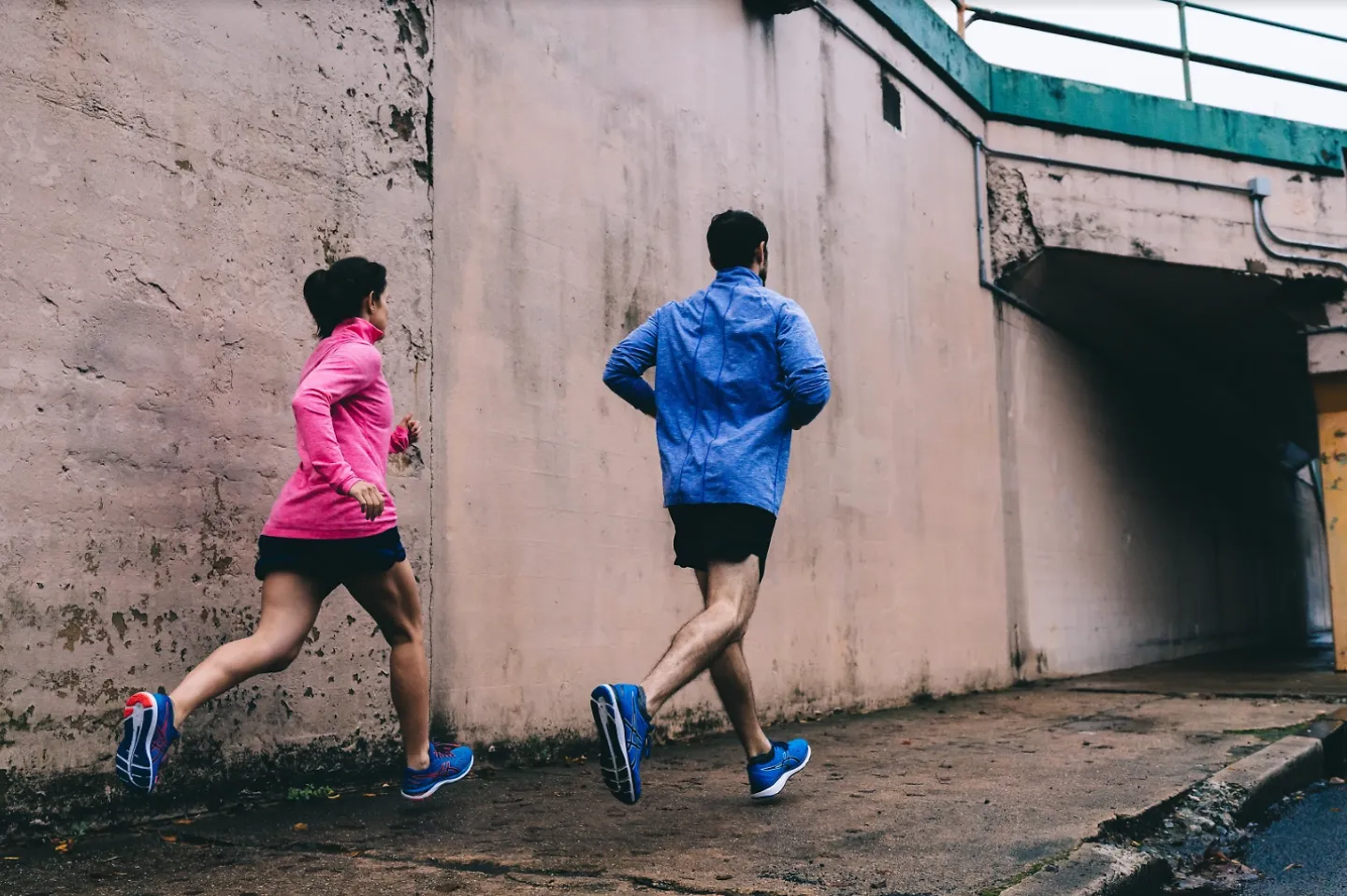 A man and woman running together while wearing ASICS apparel